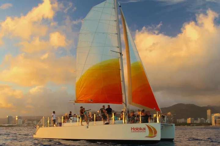 Holokai catamaran under orange sails off Waikiki