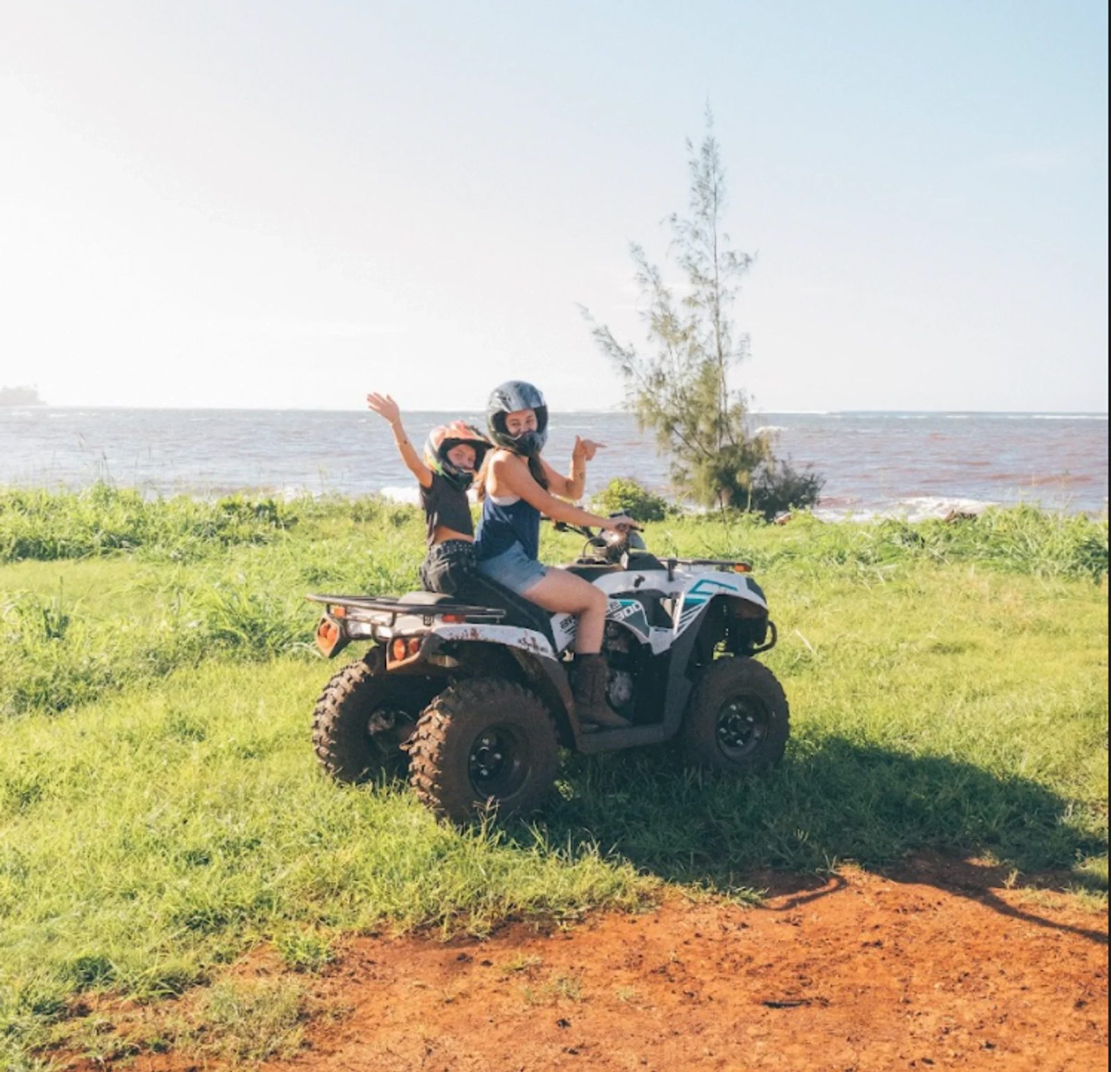 Two riders on an ATV on the grass above the shoreline in Waialua