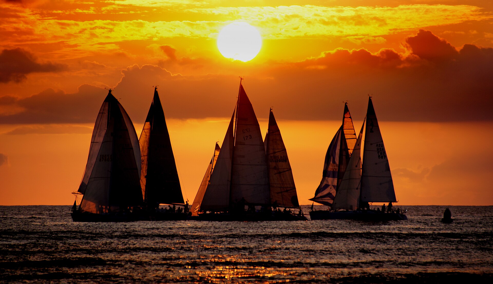 Waikīkī shoreline at sunset, Oahu — golden light over the water with surfers and hotels in background