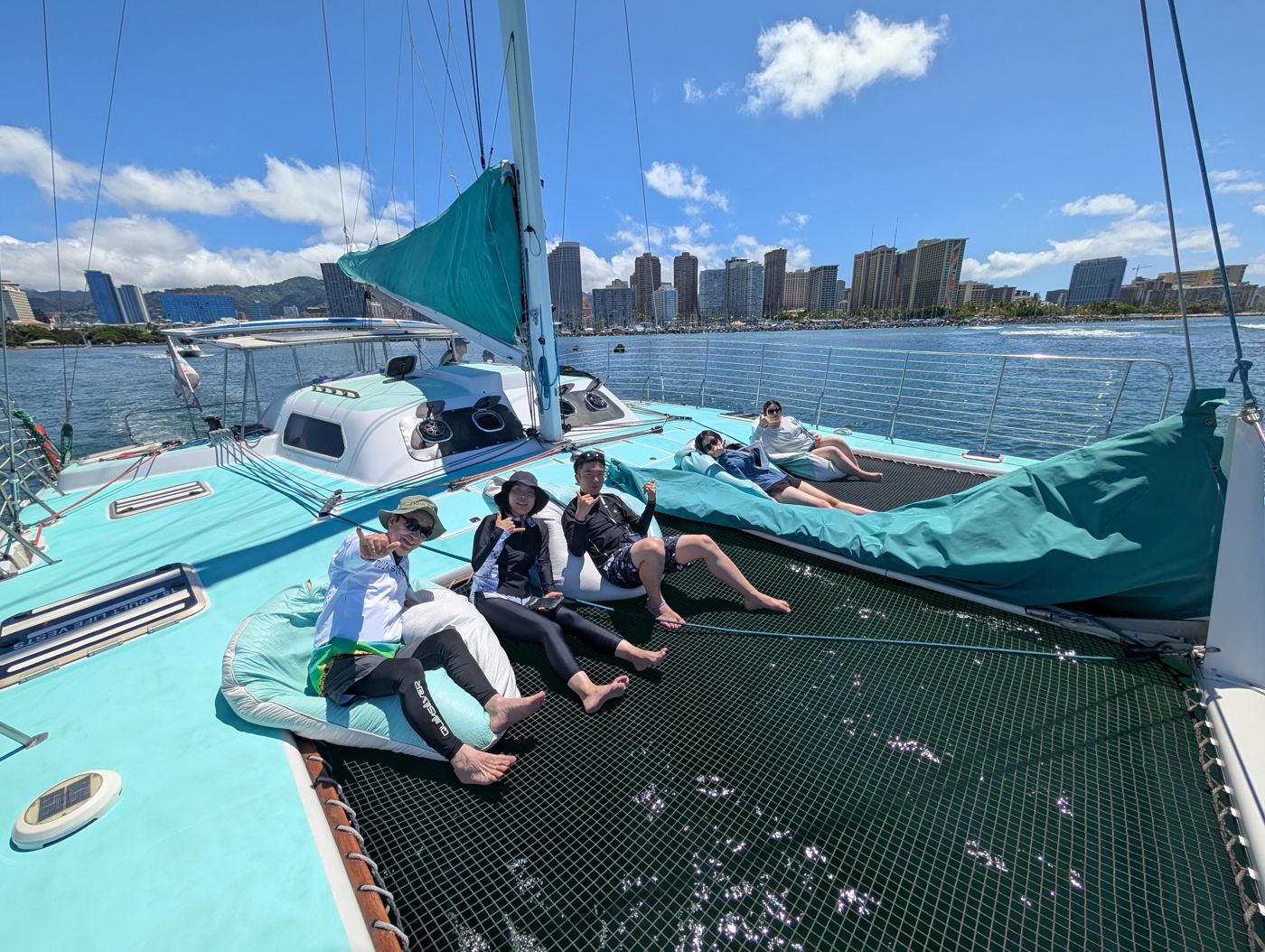 Guests relaxing on the catamaran deck with the Waikiki skyline behind